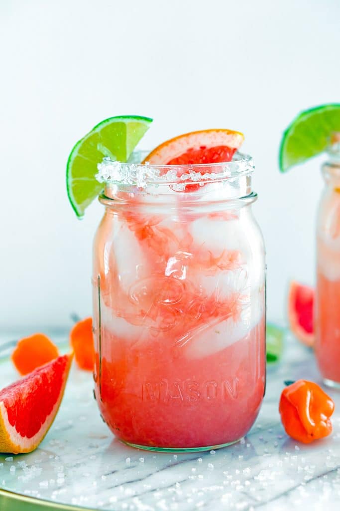 Head-on view of a spicy grapefruit margarita in a mason jar with lime and grapefruit garnish