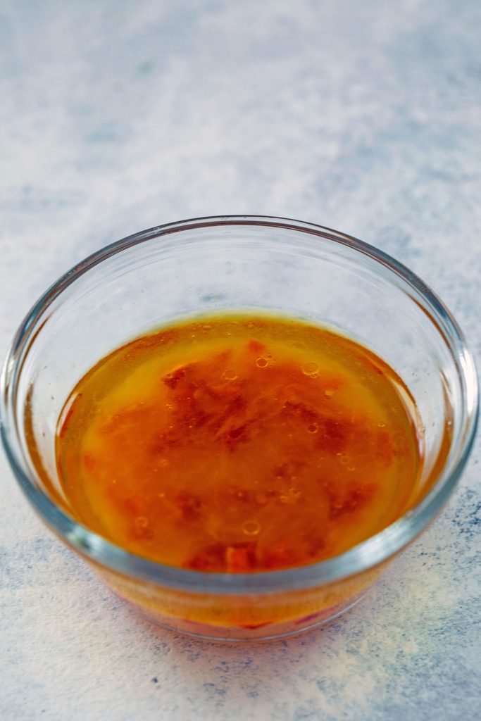 Head-on view of a small bowl of spicy lime dressing with red chili peppers