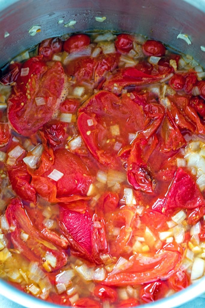 Overhead view of stockpot with roasted tomatoes, onions, peppers, and vegetable broth