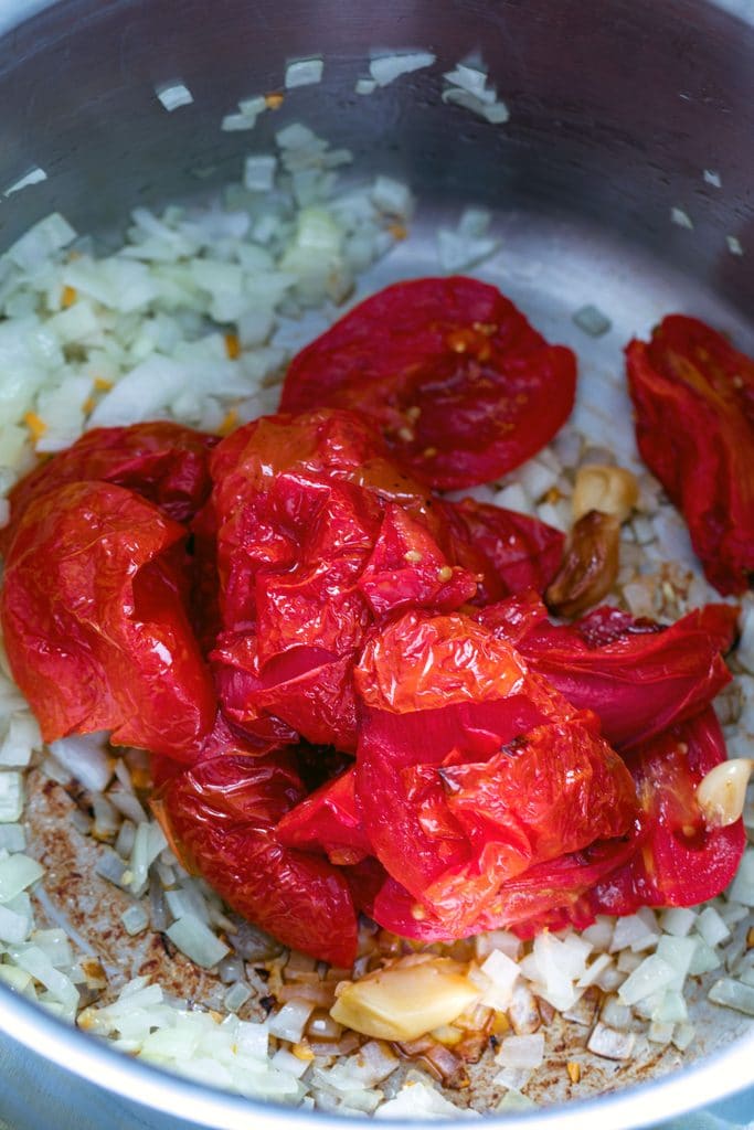 Overhead view of stockpot with onion, habanero peppers, garlic, and roasted tomatoes