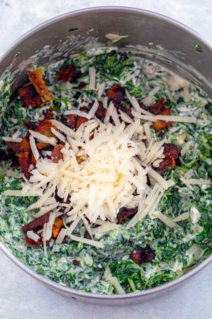 Parmesan cheese and bacon added to spinach mixture in saucepan