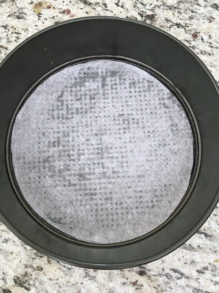 Overhead view of a round springform pan with parchment paper in it