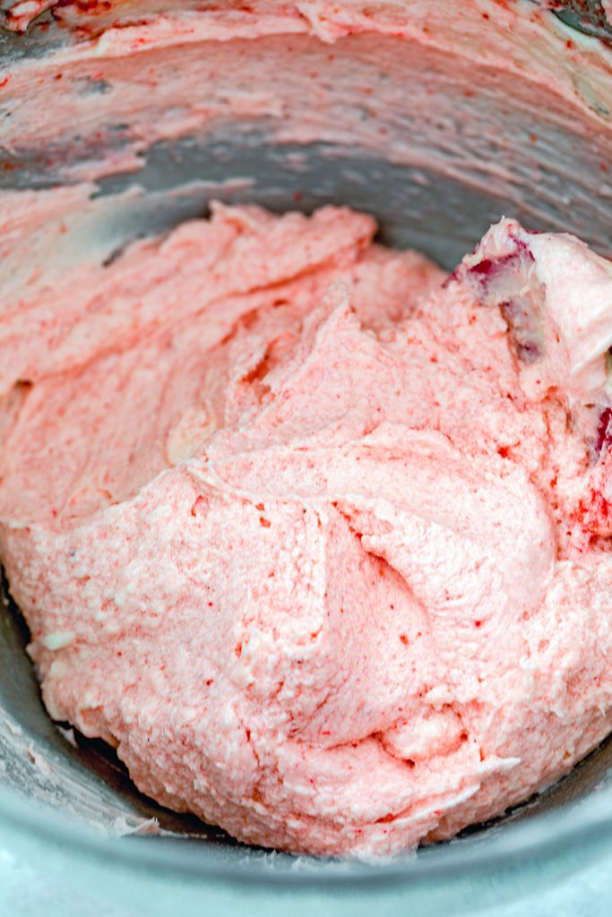 Overhead view of mixing bowl filled with pink strawberry frosting