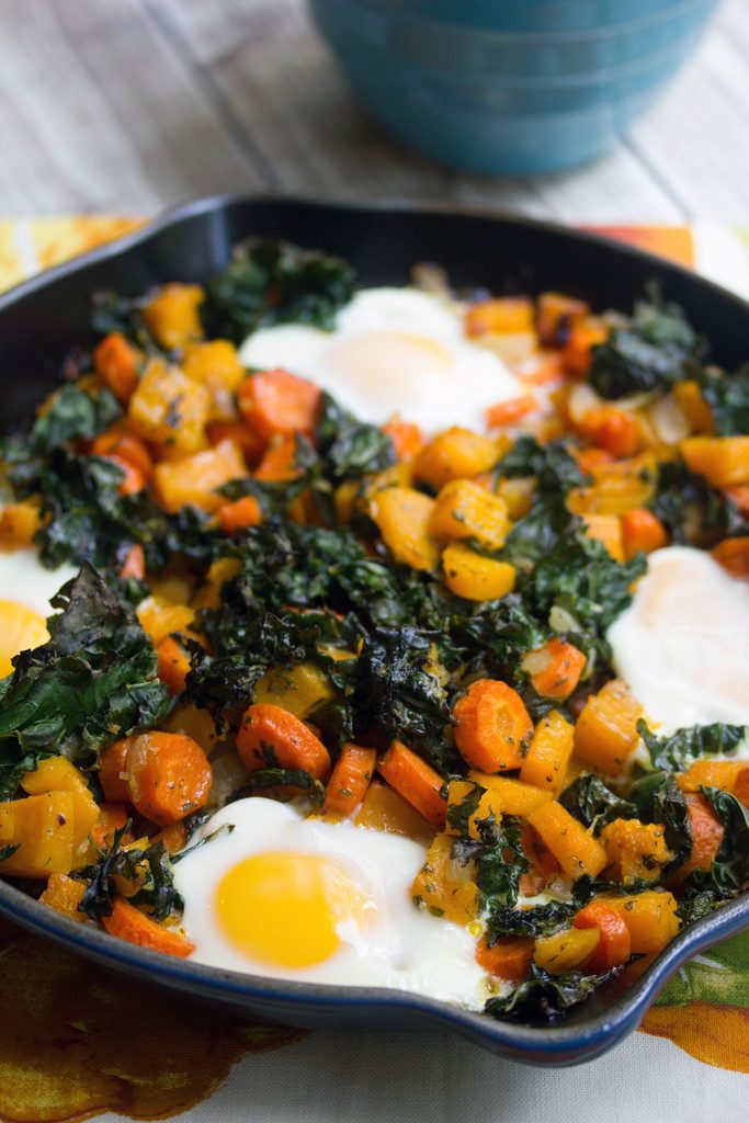 Head-on view of a cast iron skillet with squash hash with kale and eggs