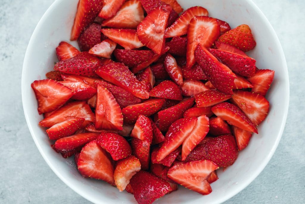 Overhead view of a bowl of strawberries macerating in sugar and triple sec