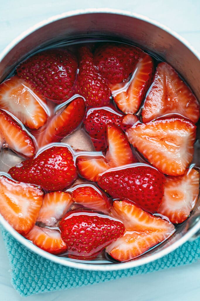 Strawberries in saucepan with water with sugar.