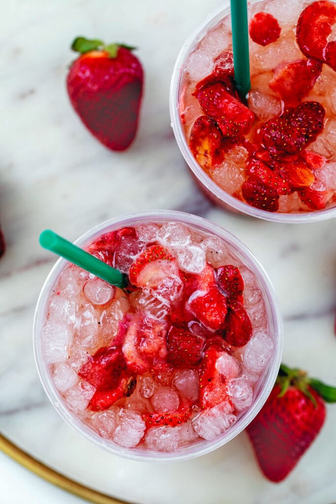 Overhead view of two cups of Strawberry Acai Refresher with cube ice and freeze-dried strawberries.