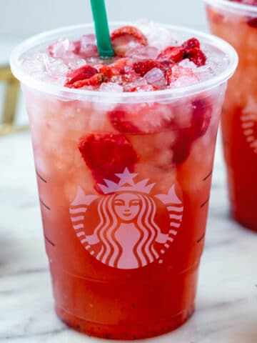 Close-up view of a Strawberry Acai Refresher in a Starbucks cup with freeze-dried strawberries.