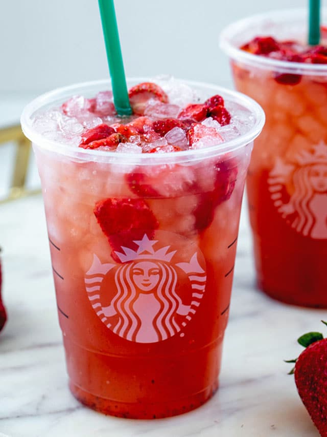 Head-on view of a Strawberry Acai Refresher in a Starbucks cup with freeze-dried strawberries.
