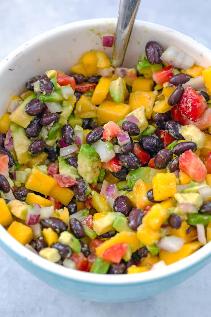 Overhead view of bowl of fruit salsa with chopped mango, strawberry, avocado, red onion, and black beans.