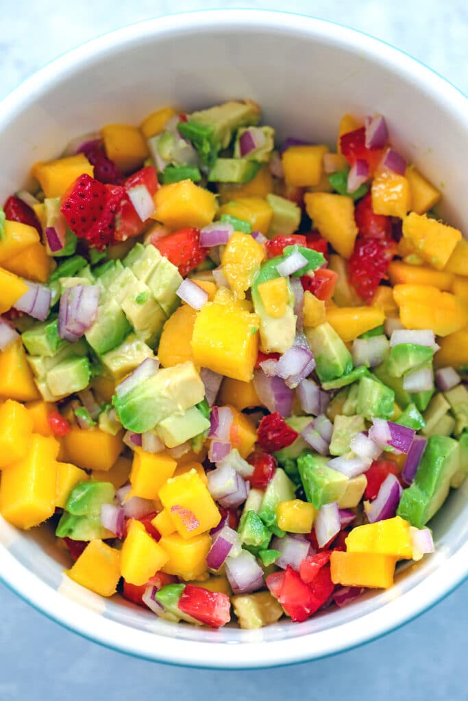 Overhead view of bowl of fruit salsa with chopped mango, strawberry, avocado, and red onion.