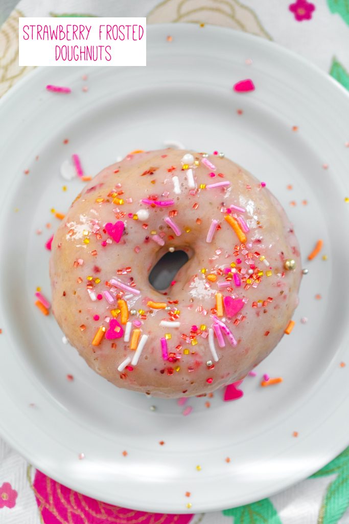 Overhead view of a Strawberry Frosted Doughnut covered in pink sprinkles on a white plate with recipe title at top
