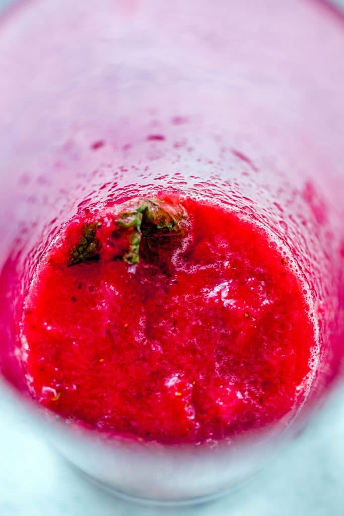 Pink cocktail shaker with strawberries and mint muddled on the bottom