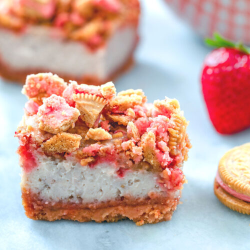 Head-on view of a strawberry shortcake cheesecake bar with strawberry shortcake oreo topping