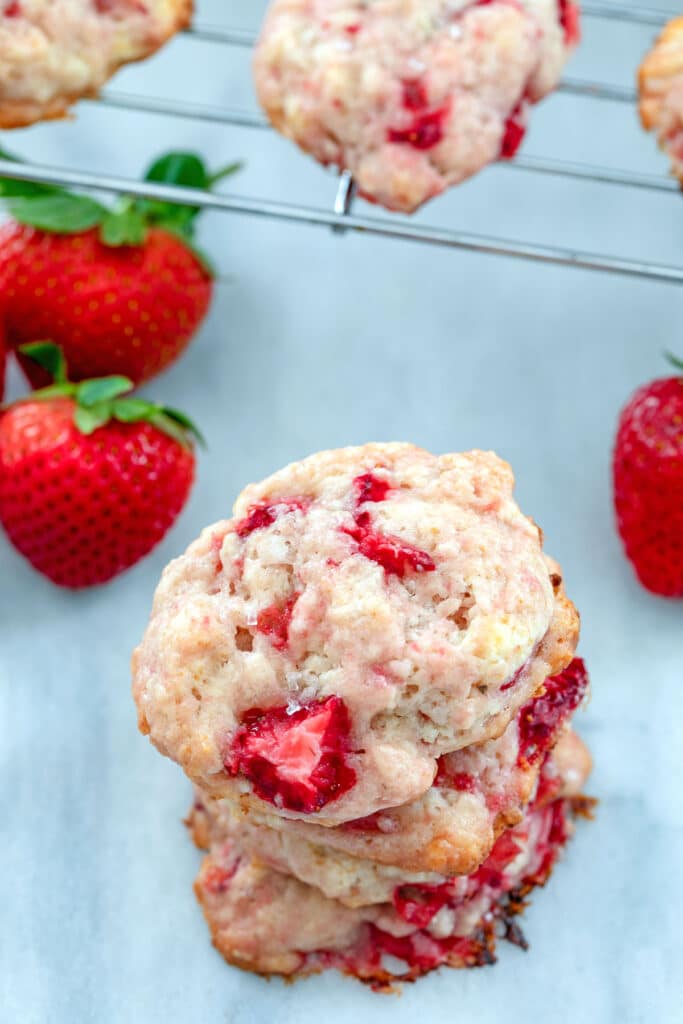 Overhead view of a stack of strawberry shortcake cookies with strawberries and more cookies in background.