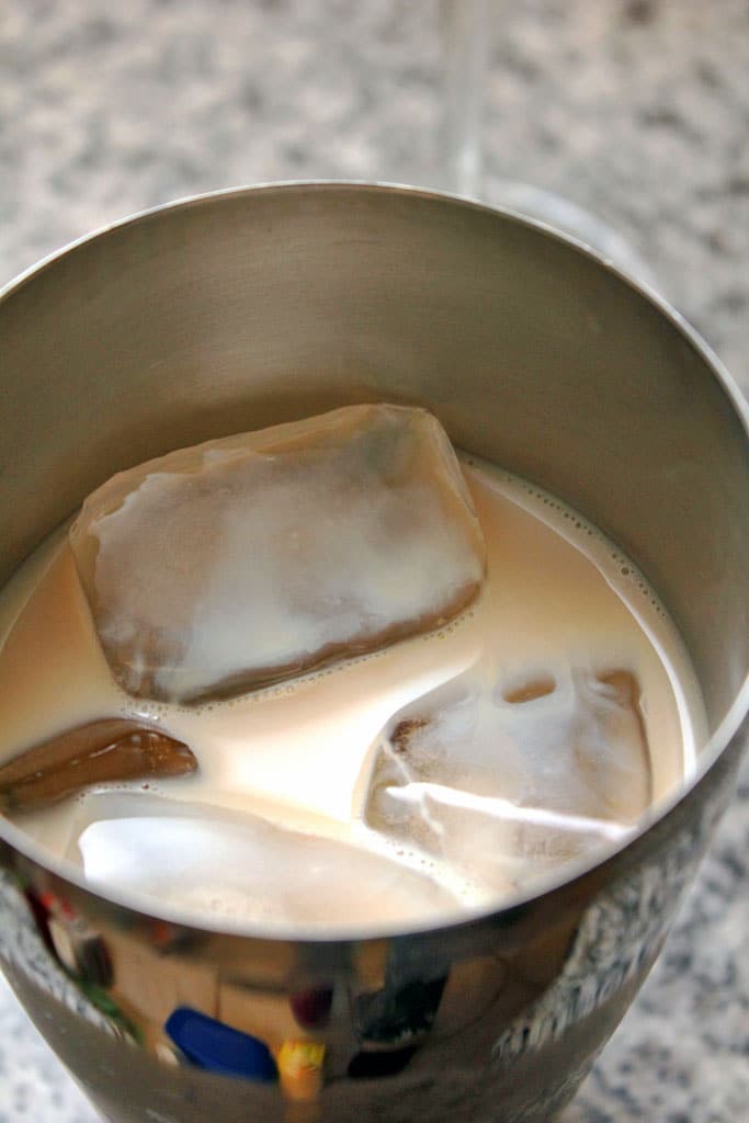 Overhead view of a cocktail shaker filled with ice, vodka, butterscotch schnapps, and milk