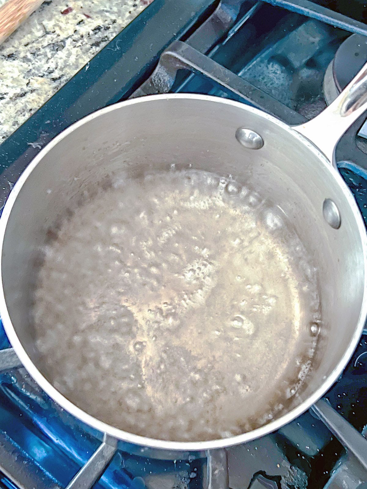 Overhead view of sugar and water simmering in saucepan.