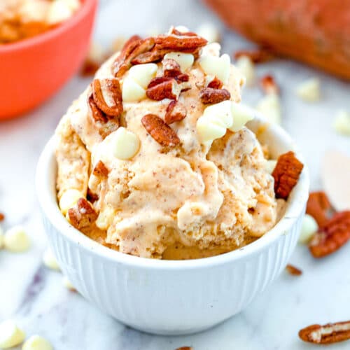Head-on closeup view of a bowl of sweet potato ice cream with pecans and white chocolate chips on top