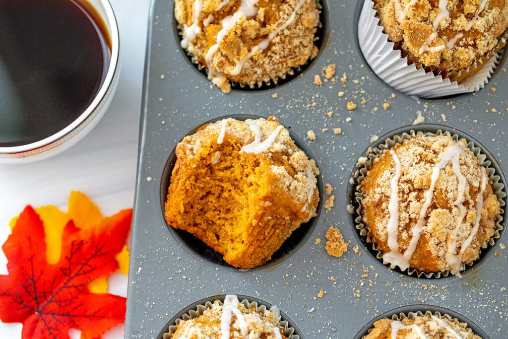 Landscape overhead view of sweet potato muffins in tin with cup of black coffee on the side.