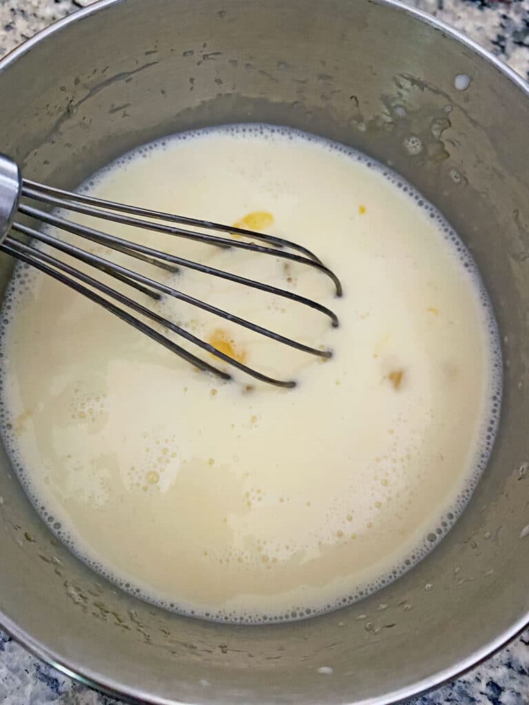 Warm milk/cream mixture poured into bowl with eggs to temper eggs.