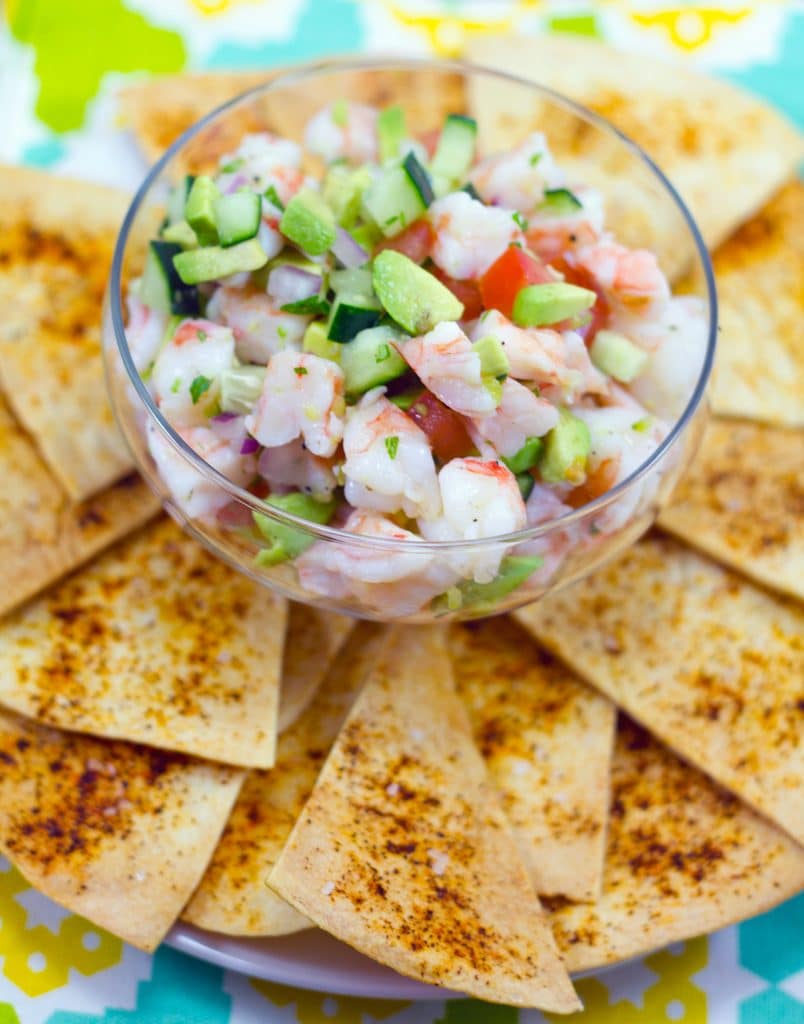 Head-on view of a clear bowl of tequila shrimp ceviche surrounded by chile dusted tortilla chips
