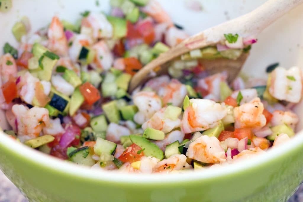 Overhead view of tequila shrimp ceviche in a serving bowl with a wooden spoon