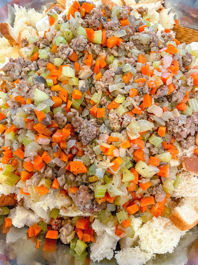 Vegetables and sausage over white bread in bowl.