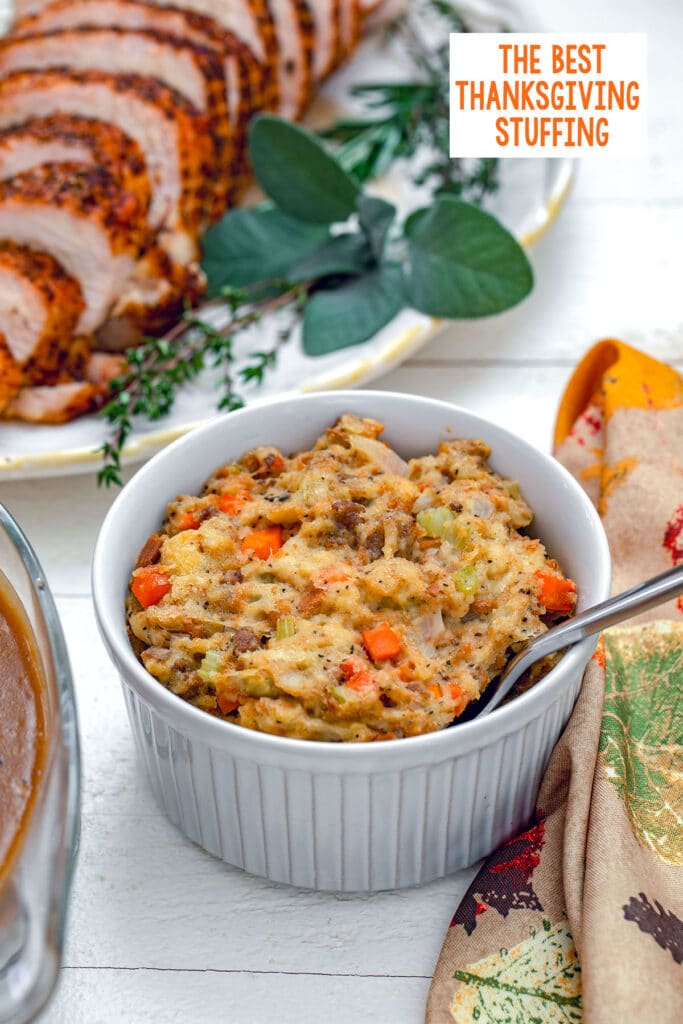 Head-on view of Thanksgiving stuffing in small casserole dish with turkey platter in background and recipe title at top.