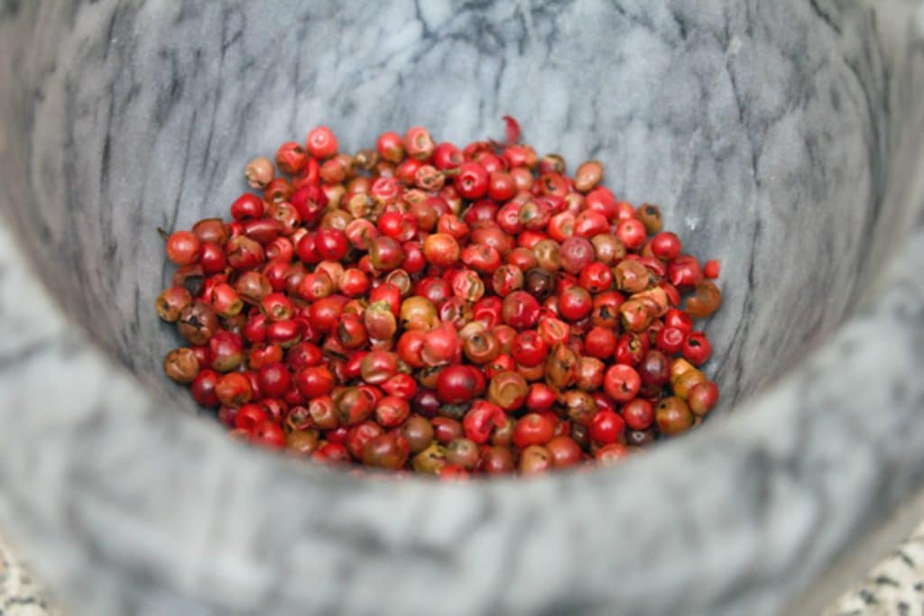 View of pink peppercorns ready to be crushed with a mortar and pestle