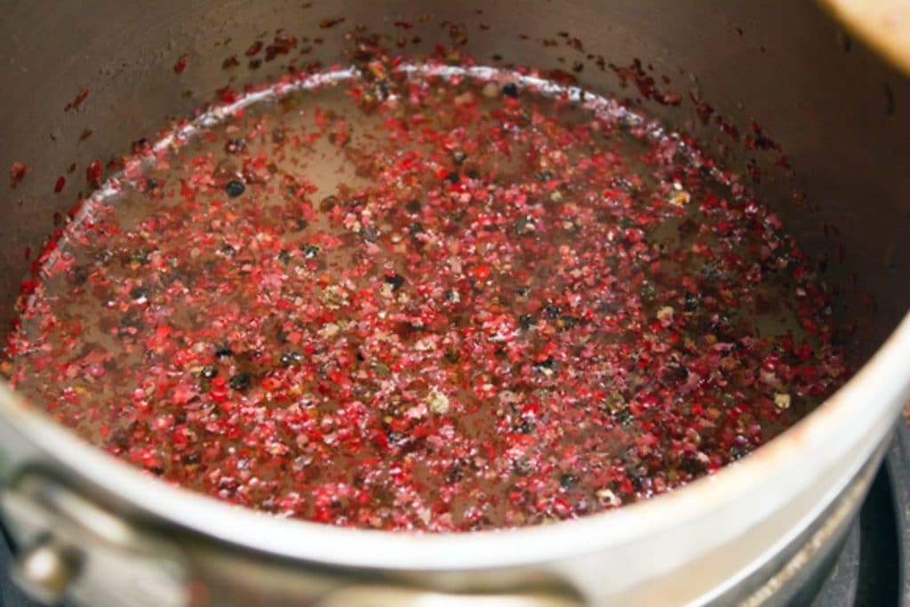 Pink peppercorns in sugar water in a saucepan for pink peppercorn simple syrup