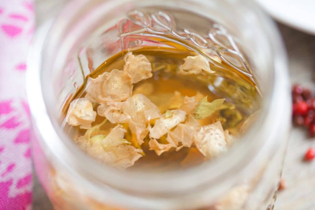 Overhead view of rosebuds in a mason jar of vodka for rose-infused vodka