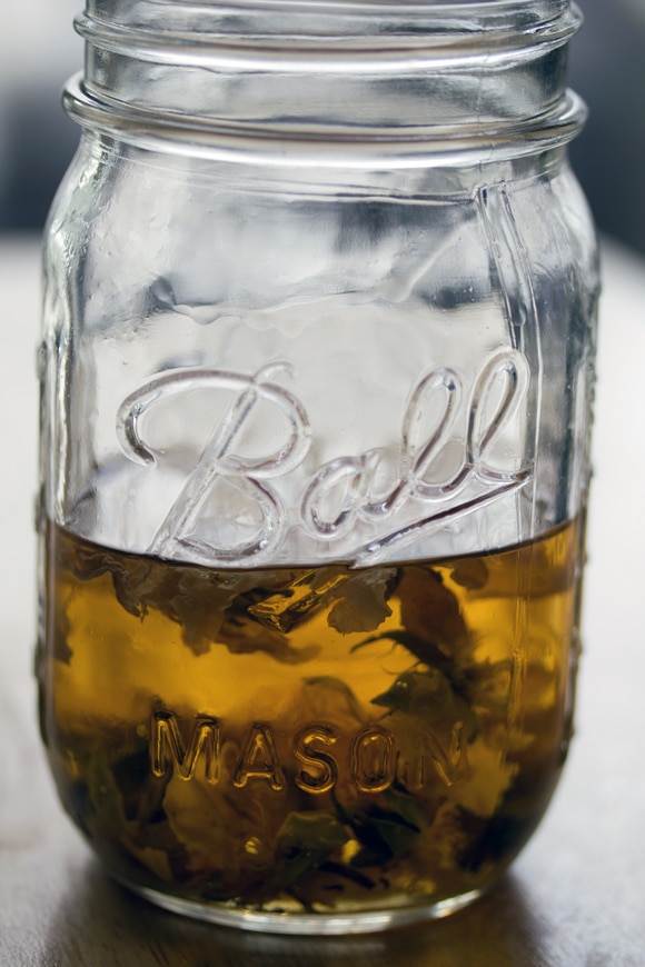 Head-on view of rosebuds in a mason jar of vodka for rose-infused vodka