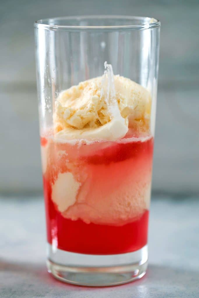 Head-on view of tall glass filled with rhubarb simple syrup, vodka, and vanilla ice cream