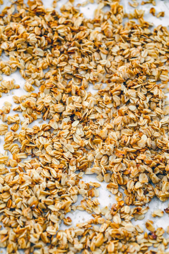 Overhead view of a baking sheet filled with toasted old fashioned oats for cookies