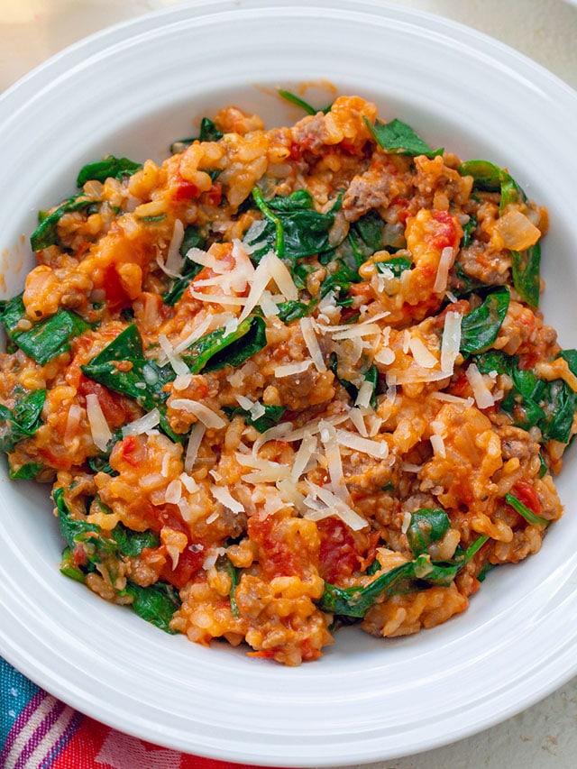 Overhead view of tomato and sausage risotto in white bowl