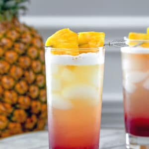 Tropical Gin Sunrise -- Tropical Gin Sunrise cocktails are a visually stunning combination of pineapple juice, gin, raspberry lambic and lemon juice. They're easy to mix and perfect for summer sipping! | wearenotmartha.com #gin #cocktails #tropicaldrinks #gindrinks