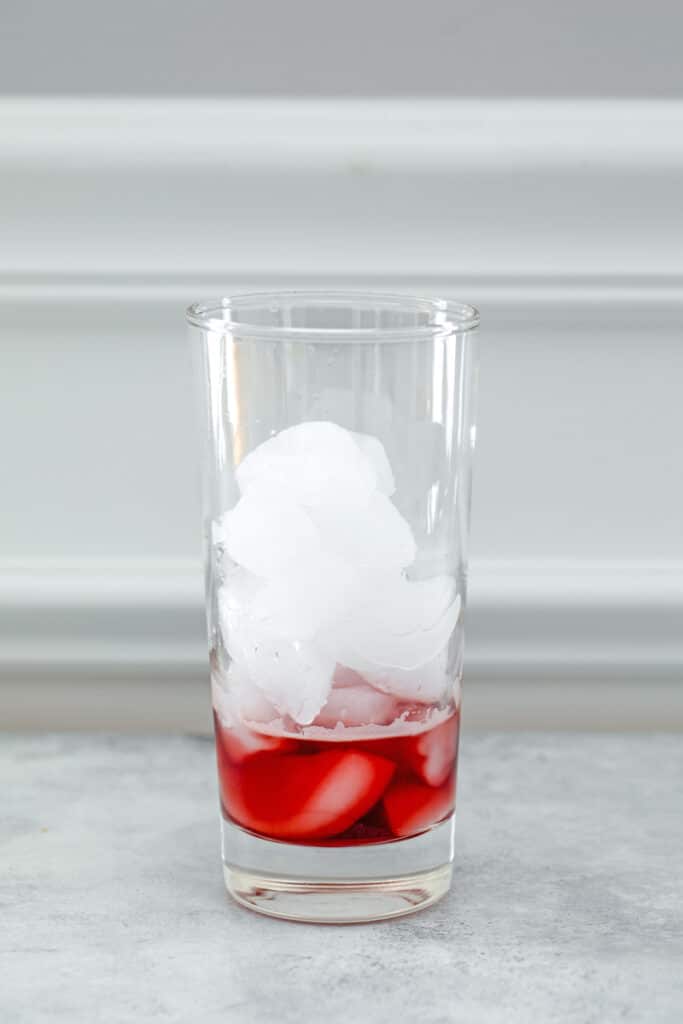 Head-on view of glass filled with ice with raspberry lambic on bottom