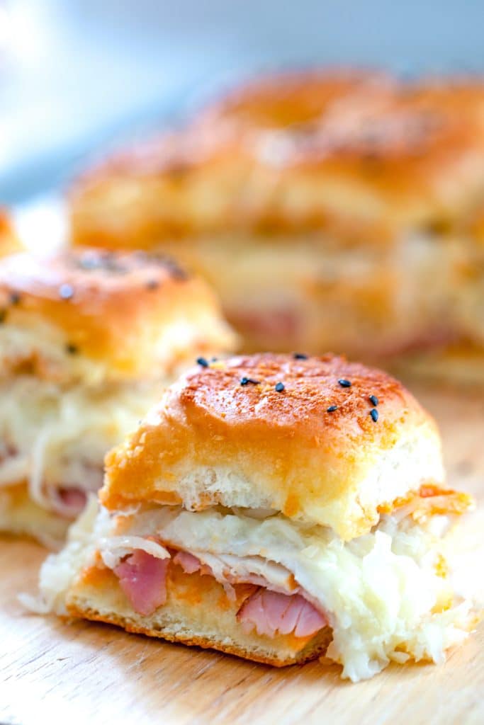 Close-up head-on view of one individual BBQ reuben slider with golden top and sauerkraut, turkey, ham, and cheese