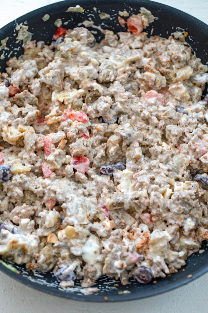 Overhead view of skillet with turkey, olive, tomato, onion, and sour cream mixture.