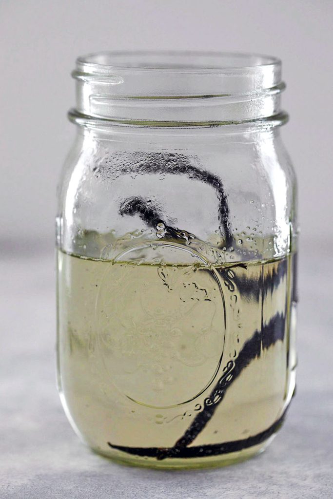 Head-on view of vanilla simple syrup with whole vanilla beans in a mason jar