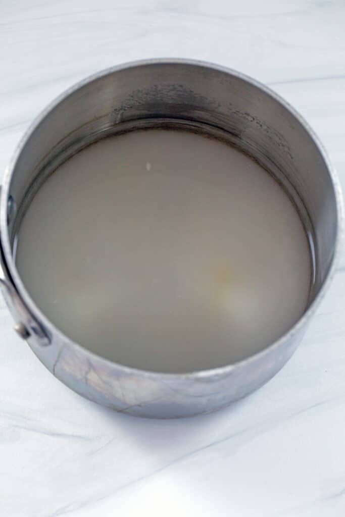 Overhead view of sugar and water in saucepan.