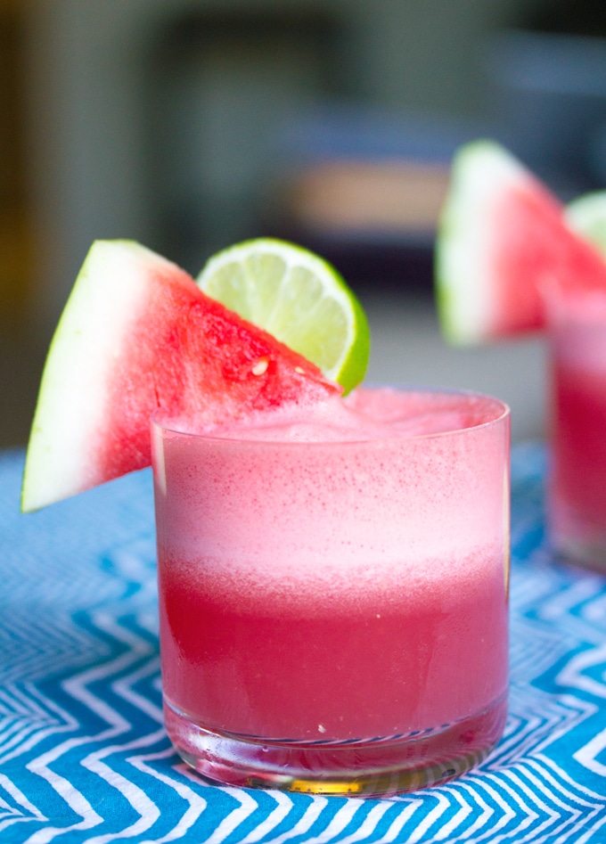 Head-on view of a watermelon coconut cocktail with watermelon wedge and lime round garnish