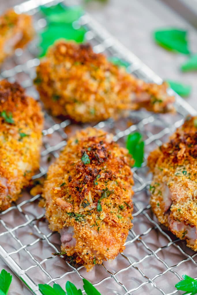 Head-on view of zesty baked chicken wings on a baking rack surrounded by chopped parsley
