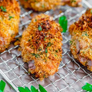 Overhead closeup view of multiple zesty baked chicken wings on a baking rack with chopped parsley all around.