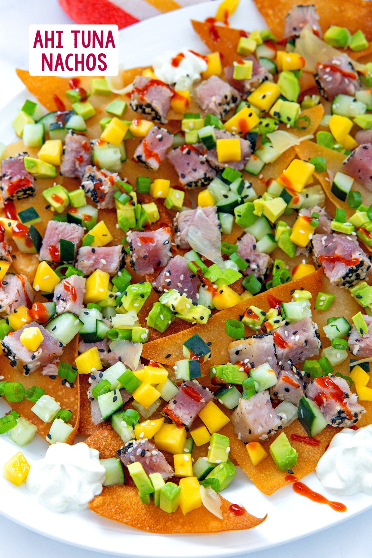 Overhead view of a platter of ahi tuna nachos with mango, cucumber, and avocado with recipe title at top.