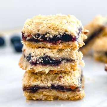 Closeup view of three almond blueberry bars stacked on each other.