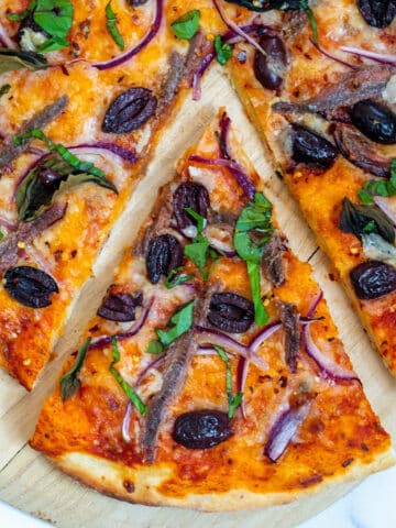 Overhead closeup view of a slice of anchovy pizza.