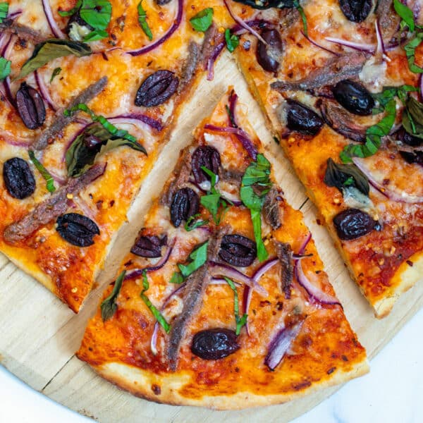 Overhead closeup view of a slice of anchovy pizza.