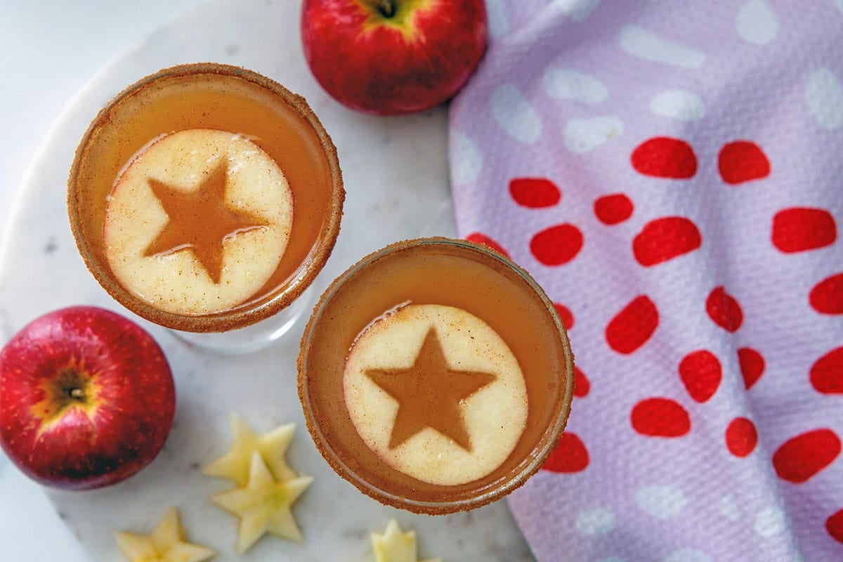 Overhead landscape view of two apple cider martinis with apple rounds with star shape cut out of them.