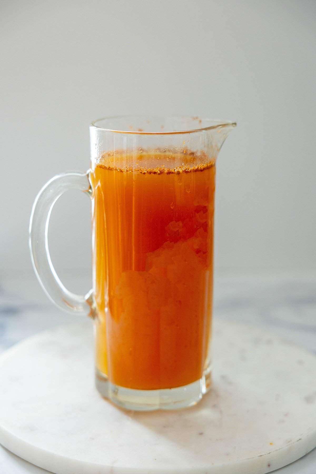Head-on view of a pitcher of apple cider mixture for popsicles.